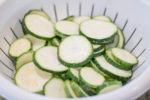 Zucchini slices tossed in salt - draining in colander