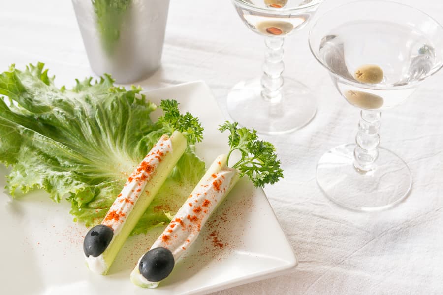 blue cheese stuffed celery sticks pictured along with two vodka martinis on a white tablecloth